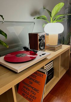 a record player sitting on top of a wooden table next to a plant and books