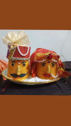 two orange faces on a plate with a bow around their head and one wearing a red hat