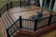 a wooden deck with wrought iron railings and chairs