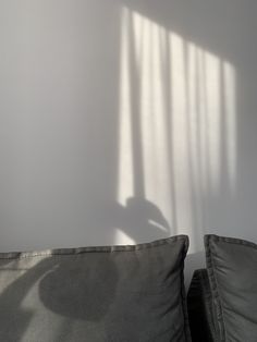 the shadow of a person's arm on a pillow in front of a white wall