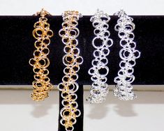 "Bubbles chainmaille bracelets a Japanese Lace 12-in-2 variation is sometimes called stepping-stones.  These chainmail bracelets are made with 4 mm, 6 mm, and 9 mm silver-plated and gold-plated rings, with small silver-plated or gold-plated lobster clasps.  These are currently 7.5\" inches long but the length can be adjusted upon request for no additional charge. A. Silver-plate on silver-plate B. Silver-plate on silver-plate with extra inside rings C. Gold-plate on silver-plate with extra insid Chainmail Bracelet, Pattern Bracelet, Wire Tree Sculpture, Photo Gold, Chainmaille Bracelet, Chain Maille Jewelry, Pet Bows, Gold Plated Rings, Cairo