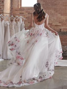 a woman in a white dress is looking at some dresses