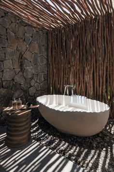 a bathtub sitting in the middle of a room next to a stone wall and floor