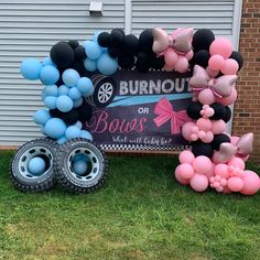 a bunch of balloons that are sitting in the grass near a sign and some tires