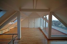 an empty room with wooden floors and large windows on each side of the wall, looking out onto rooftops