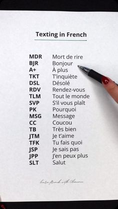 a person holding a pen over a paper with some writing on it that says texting in french