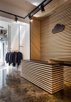 a clothing store with clothes hanging on the wall and an open closet behind it that has wooden slats