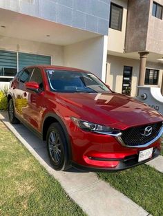 a red mazda cx - 5 parked in front of a house