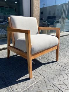 a wooden chair sitting on the side of a road next to a store front window