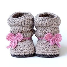 a pair of crocheted baby booties with pink bows on the front and bottom