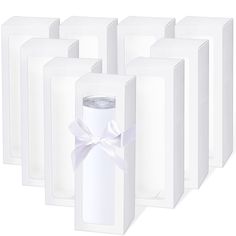 six white boxes with a ribbon tied around the top and one empty bottle in front