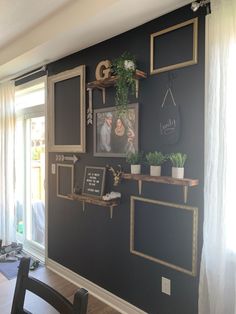 the wall is painted black with gold trim and pictures on it, along with some plants