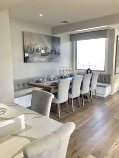 the dining room table is set with white chairs and gray upholstered bench seats