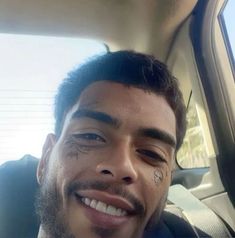 a close up of a person in a car with tattoos on his face and nose