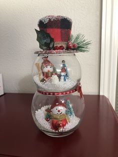 three snow globes with christmas decorations in them on top of a red table next to a white wall