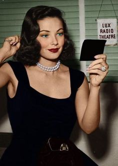 a woman in a black dress is holding up a sign that says lux radio theatre