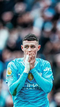 a soccer player holding his hands to his face while standing in front of an audience