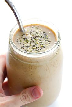 a hand is holding a spoon in a jar filled with cream and chia seeds