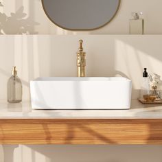 a white sink sitting on top of a wooden counter next to a mirror and soap dispenser