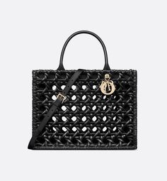 Maria Grazia Chiuri's hallmark Dior Book Tote is presented in an elegant new variation. Made in black braided calfskin displaying the openwork Cannage motif, it is embellished with antique gold-finish metal D.I.O.R charms. The interior reveals a zip pocket and slip pockets, ideal for organizing all the daily essentials. Featuring an adjustable and removable strap, the medium tote exemplifies Dior savoir-faire and may be carried by hand or worn over the shoulder.. Dior Book, Luxury Tote Bags, Book Tote Bag, Dior Book Tote, Maria Grazia Chiuri, Designer Totes, Maria Grazia, Wallet Pouch, Essential Bag