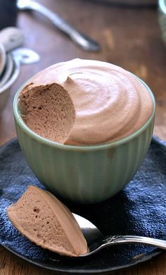 a bowl of chocolate pudding on a plate with a spoon