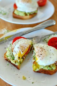 an egg and tomato sandwich is on a white plate with a fork next to it