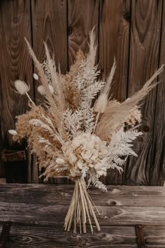 a bouquet of dried flowers sitting on top of a wooden table next to a fence