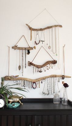 there is a wall hanging made out of branches and jewelry on the shelf next to it