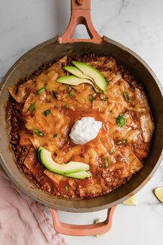 a skillet filled with food sitting on top of a counter next to sliced avocados