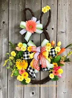 a wreath with flowers and bows hanging on a wooden fence