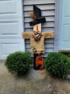 a scarecrow made out of burlock and fabric sitting in front of a house