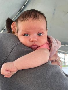 a close up of a baby holding on to someone's back in a tent