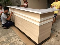 two men working on a reception desk in front of a group of people standing around