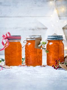 three jars filled with liquid sitting on top of snow covered ground next to christmas decorations