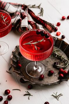 cranberry martinis with rosemary garnish on the rimmed glasses are ready to be served