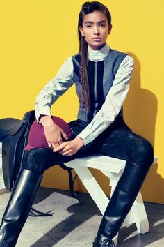 a woman is sitting on a bench wearing black leather pants and a turtle neck sweater