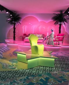 a living room filled with furniture and palm trees next to a neon pink wallpaper