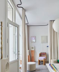 a living room filled with furniture next to a window covered in curtains and drapes