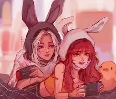 two women in bunny ears are laying on a bed and one is holding a cell phone