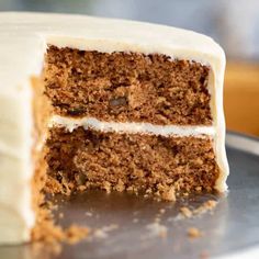 a close up of a cake with white frosting on a metal platter in front of a wooden table