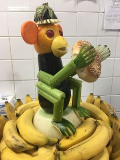 a statue of a rat holding a hamburger and some bananas