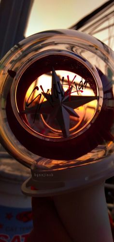 a hand holding a glass clock with the sun setting in the background