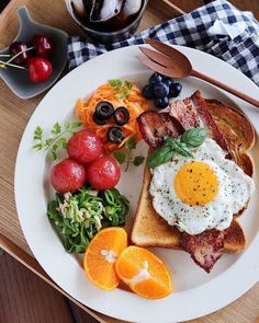 a breakfast plate with eggs, bacon, and fruit