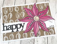 a card with a flower on it and the words happy written in black ink, sitting on top of a wooden table