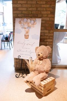 a teddy bear sitting on top of a wooden crate in front of a sign that says congratulations