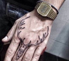 a man's hand with a deer head tattoo on it and a wrist watch