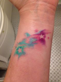 a person's arm with a tattoo on it that has blue and pink ink