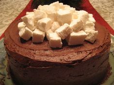 a chocolate cake topped with marshmallows on top of a red table cloth