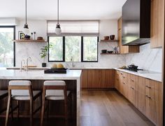 a kitchen with wooden cabinets and white marble counter tops, along with two bar stools