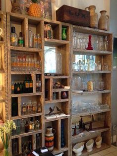 an old wooden shelf filled with lots of bottles and glasses on top of tiled flooring